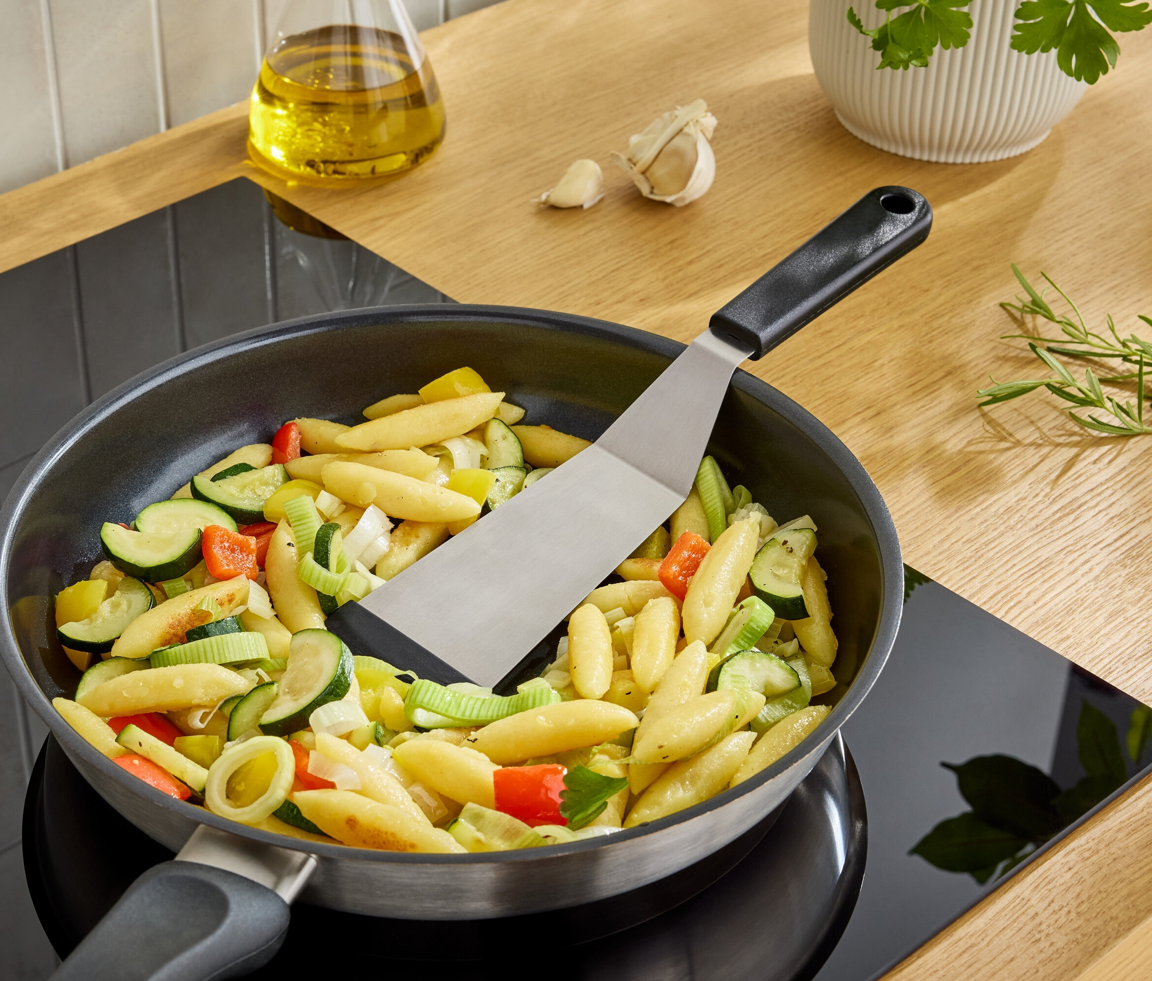 Spatula, ocaktaki tavada sebzeli erişteyi çeviriyor.