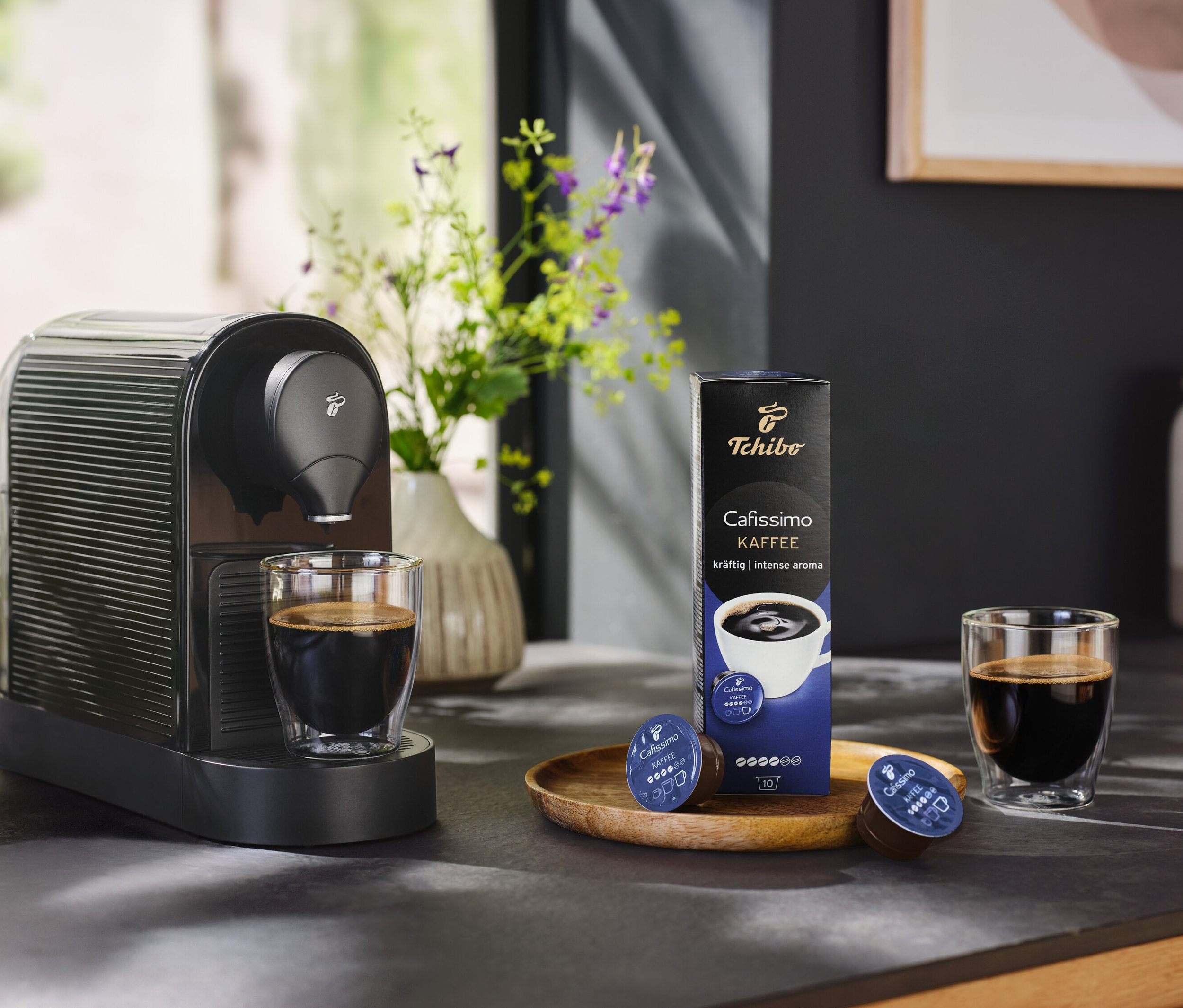 Bir fincan kahve ve bir paket kahve kapsülü ile birlikte siyah Cafissimo pure+.