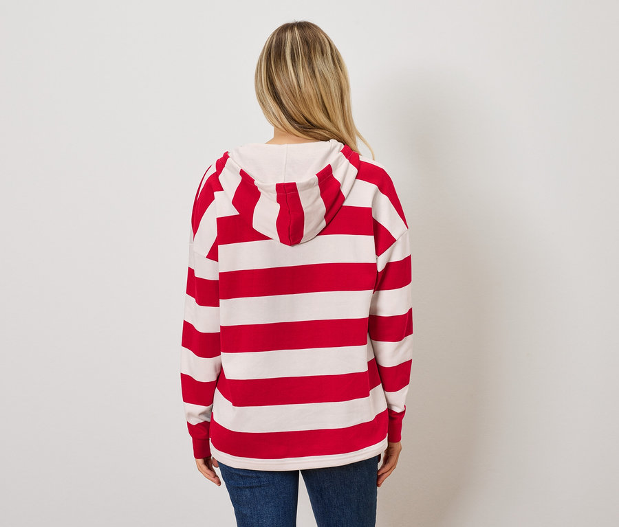 Kameraya arkası dönük bir kadın, kırmızı ve beyaz çizgili kapüşonlu bir sweatshirt ve mavi kot pantolon giyiyor.