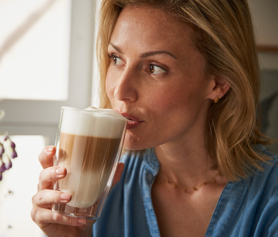 Kadın çift cidarlı bardaktan latte macchiato içiyor.