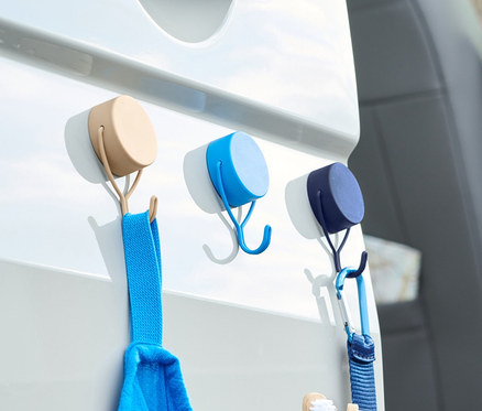 Üç adet mıknatıslı askı, beyaz bir araba kapısında mavi bir havlu ve bir makyaj çantasını tutuyor.