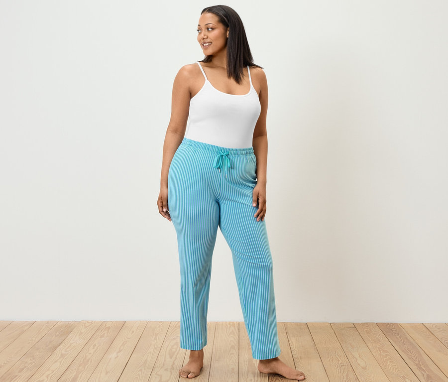 Pijama altı ve atlet giyen bir kadın ayakta duruyor.