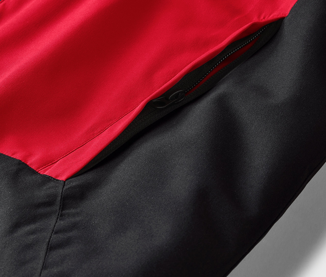 Cepli fermuarlı, kırmızı ve siyah bir ceketin yakın çekim detayı.