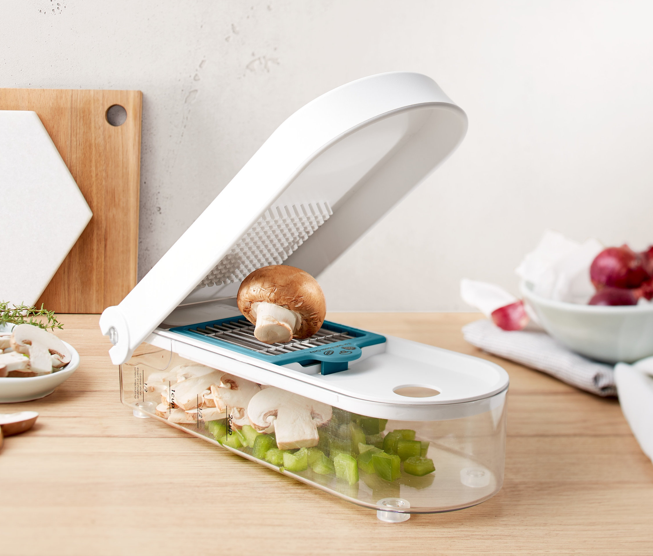 Doğranmış mantar ve yeşil biber dolu şeffaf hazneli, beyaz sebze ve meyve doğrayıcının üzerinde kahverengi mantar.