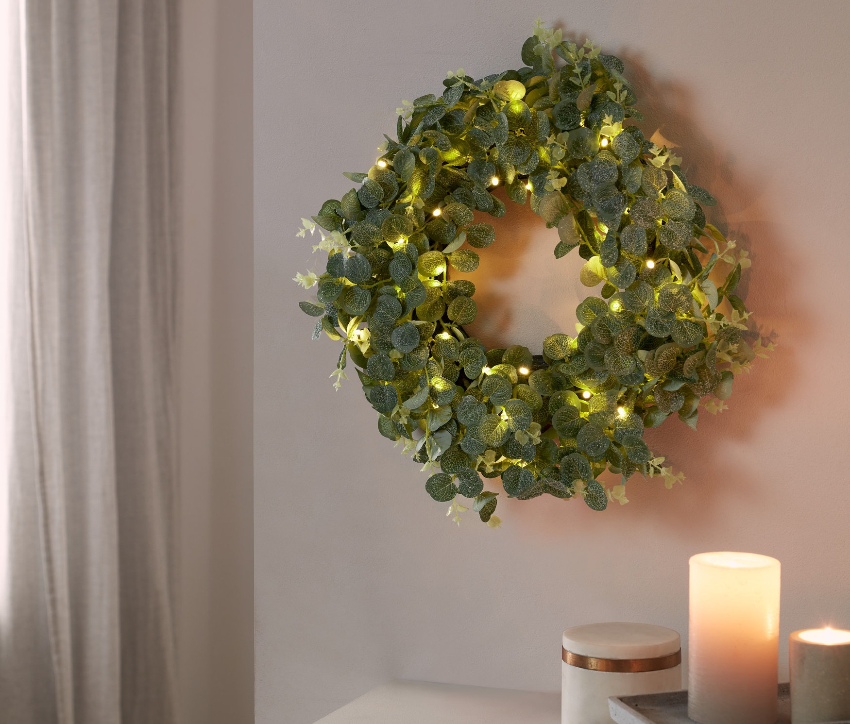 Duvarda LED'li dekoratif çelenk asılı duruyor.