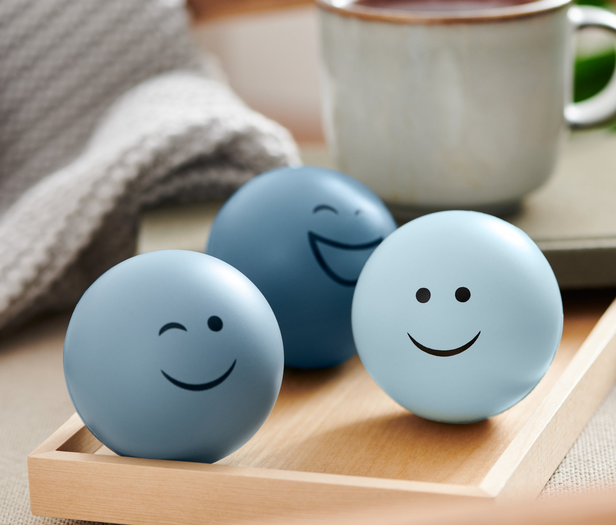 Ahşap bir tepside yüzleri olan üç adet stres topu.