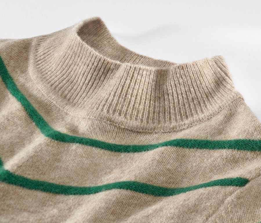 Krem rengi, dik yakalı, çizgili örgü kazağın yakın çekimi.