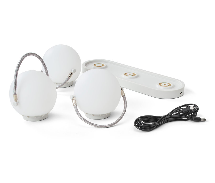 Beyaz arka planda üç adet şarjlı masa lambası, şarj istasyonu ve kablo.