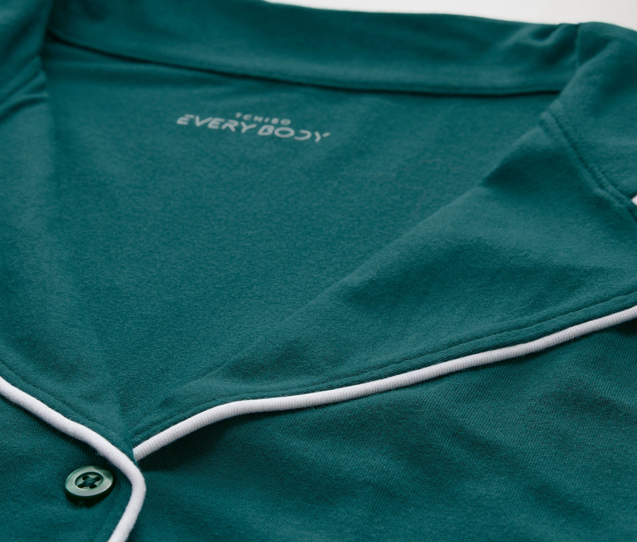 Beyaz şeritli ve düğmeli yeşil bir pijama üstünün yakın çekim görüntüsü.