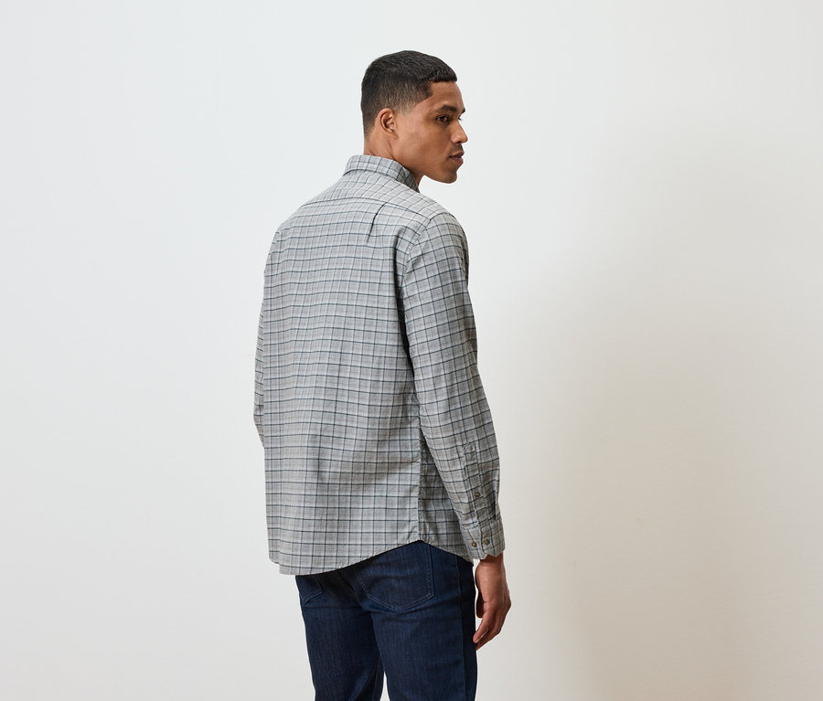 Kareli gömlek ve koyu renk kot pantolonlu bir adam izleyiciye arkası dönük duruyor.