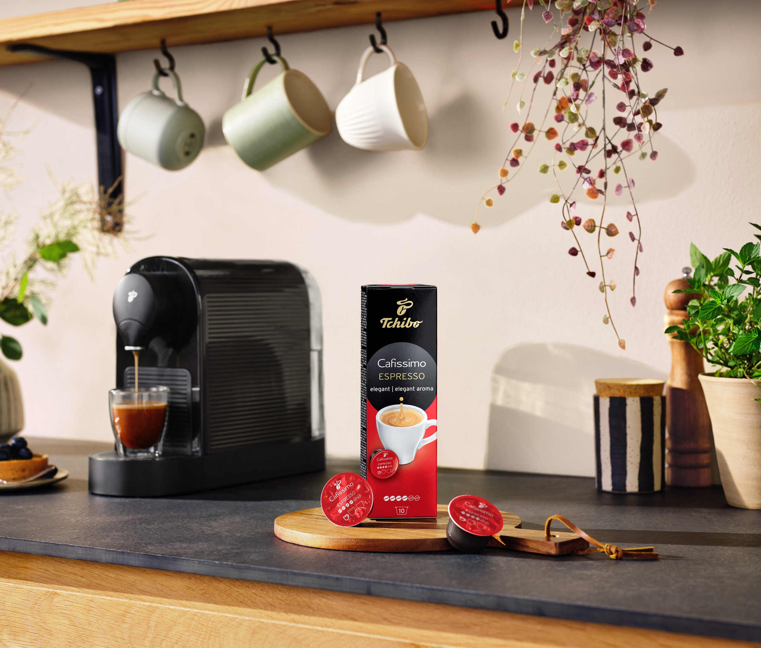 Espresso makinesi, bir bardak Cafissimo Espresso Elegant Aroma paketinin yanına kahve döküyor.