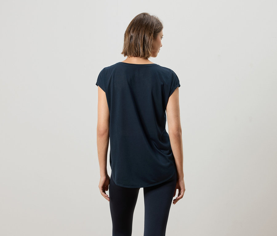 Kısa kahverengi saçlı bir kadının koyu lacivert tişört ve tayt giydiği arka görünümü.