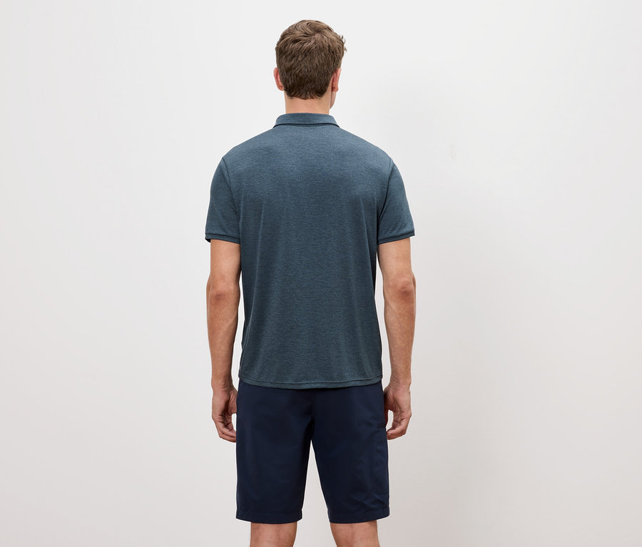 Beyaz bir arka plan önünde, mavi kırçıllı bir polo tişörtü ve şort giyen bir adamın arka görünümü.