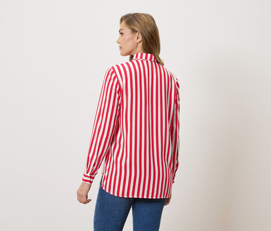 Arkadan kırmızı beyaz çizgili bluz ve kot pantolonlu kadın.