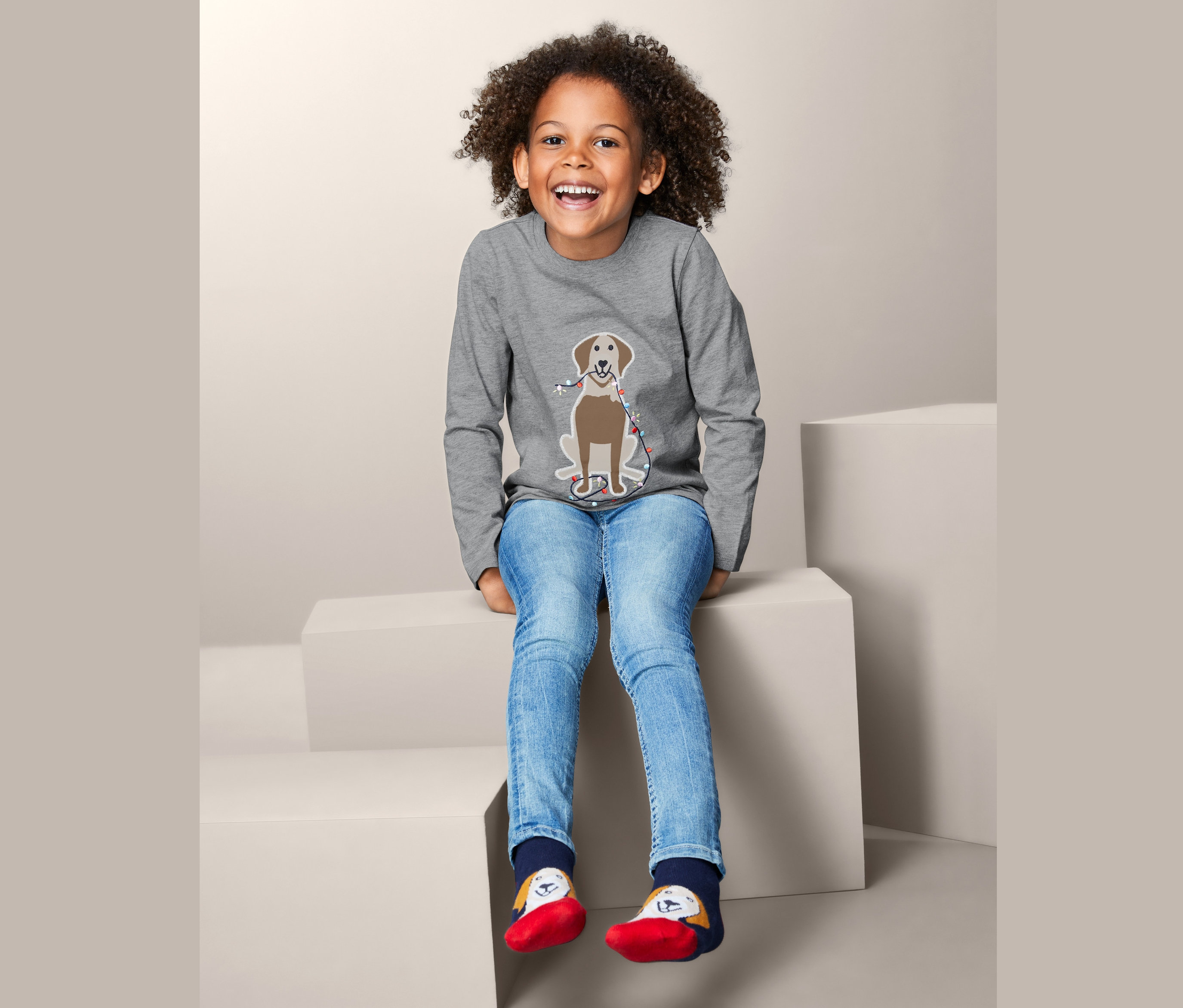 Merdivenlerde oturan bir kız, köpek desenli gri uzun kollu tişört giyiyor.