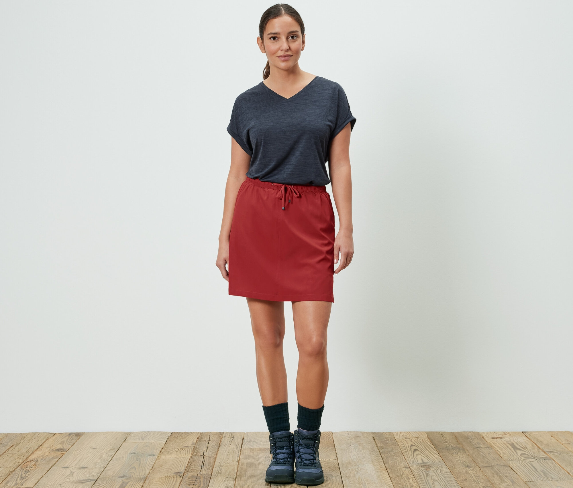 Kadın kırmızı fonksiyonel şort etekle poz veriyor.