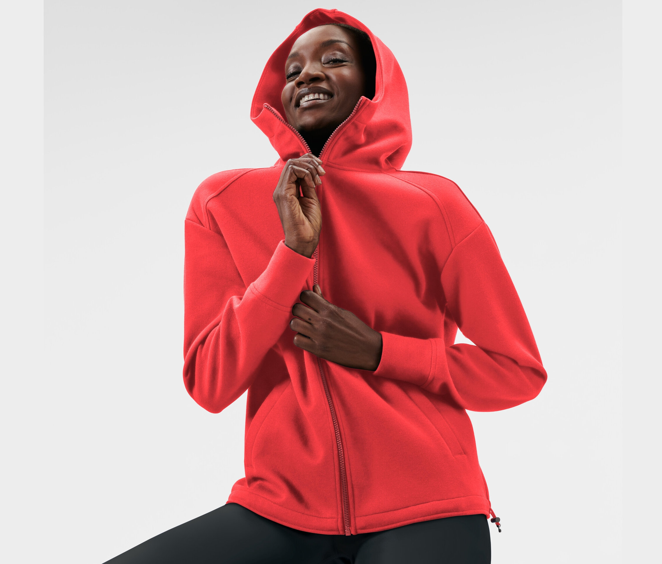 Kadın kırmızı kapüşonlu sweatshirt ceketini kapatıyor.