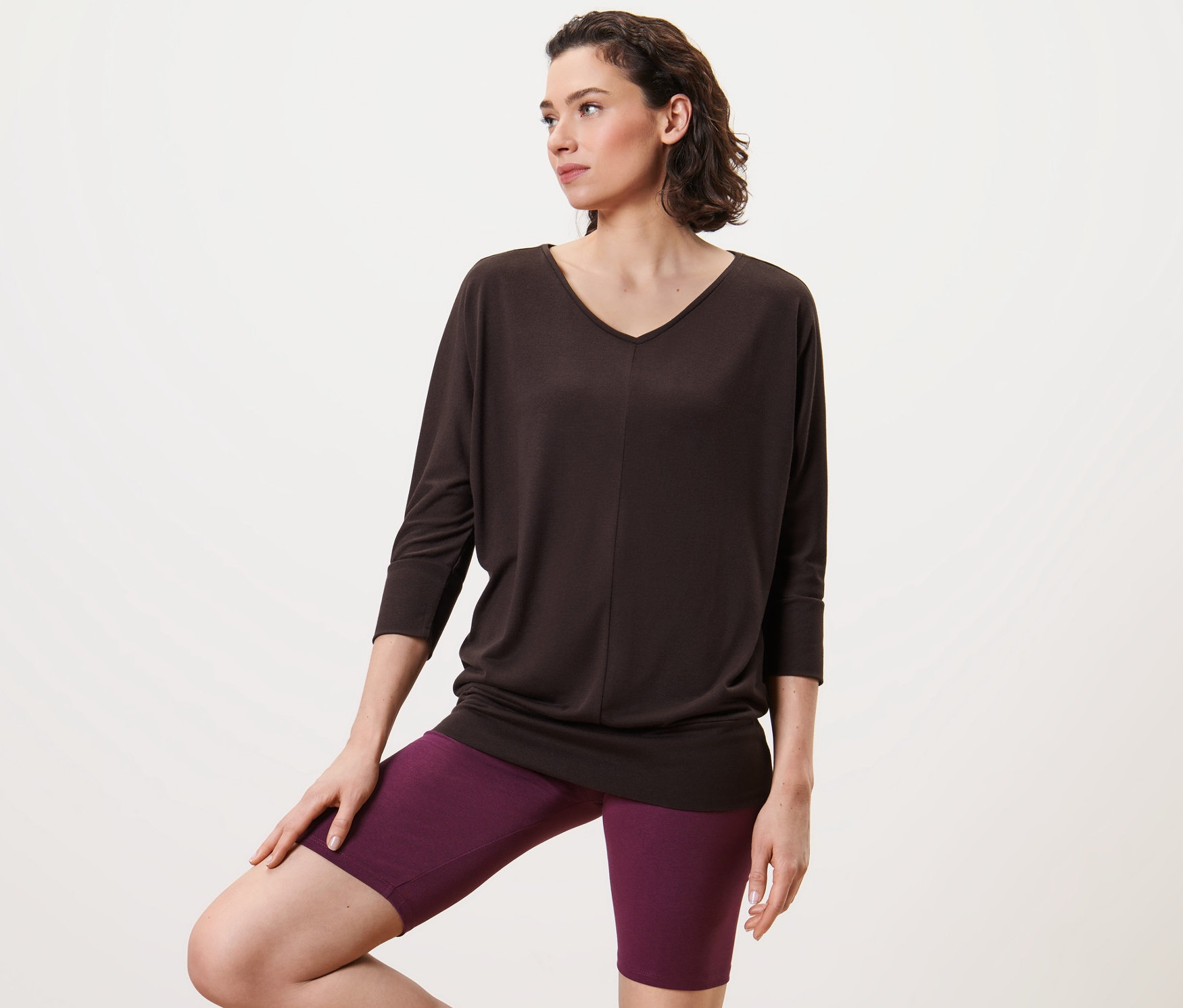 Kadın Yoga Üstü, Çikolata Rengi ve mor şortla poz veriyor.