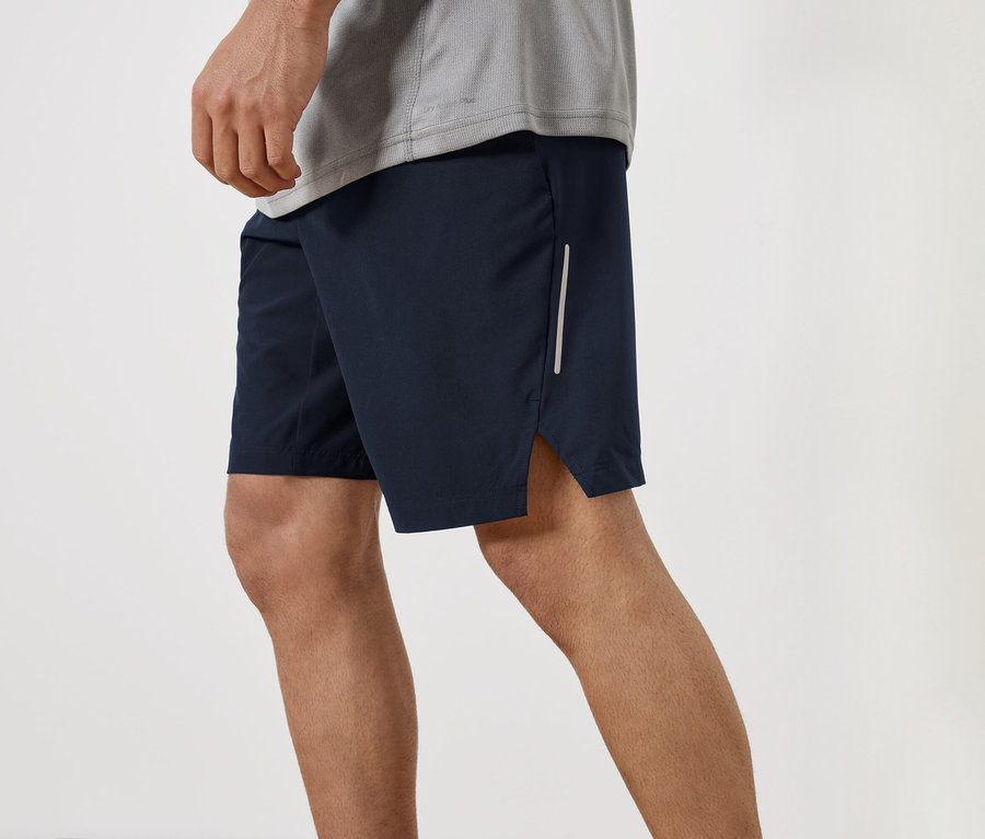 Bir adam lacivert şort ve gri bir tişört giyiyor.