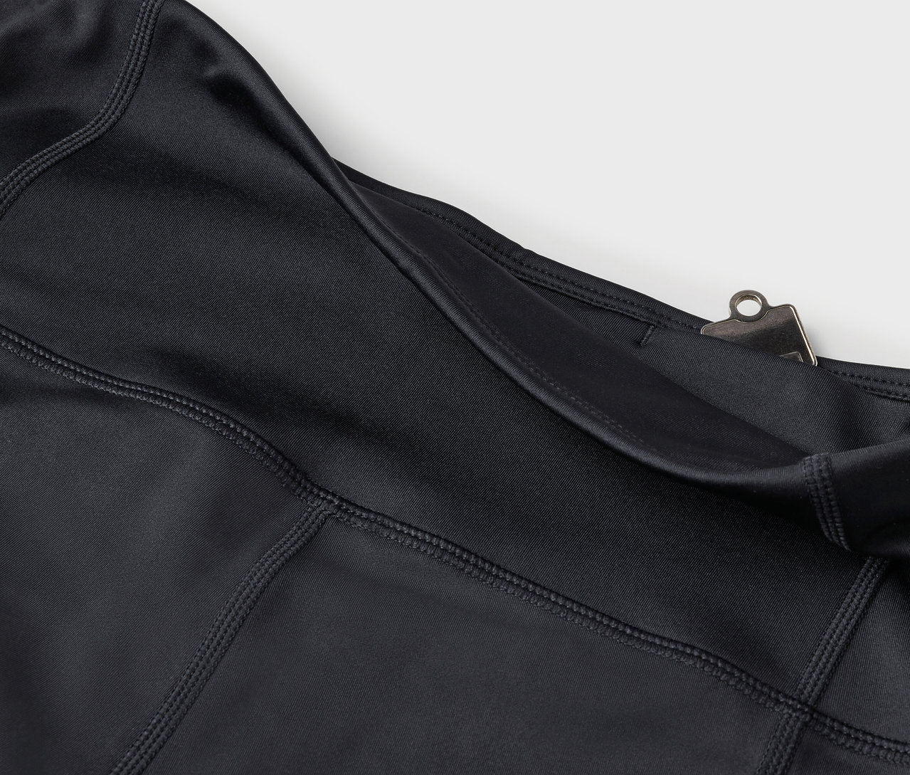 Cebi ve gümüş rengi klipsi olan siyah tayt detayı.