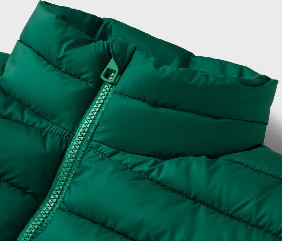 Yakası ve fermuarı olan yeşil kapitone bir ceketin yakın çekimi.
