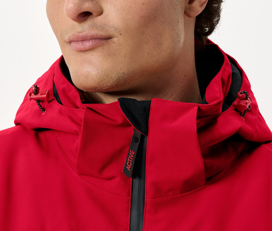 Adam kapüşonlu kırmızı bir ceket giyiyor.