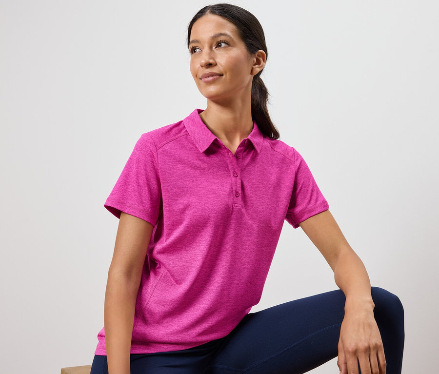 Kadın pembe polo tişört ve lacivert tayt giyiyor.