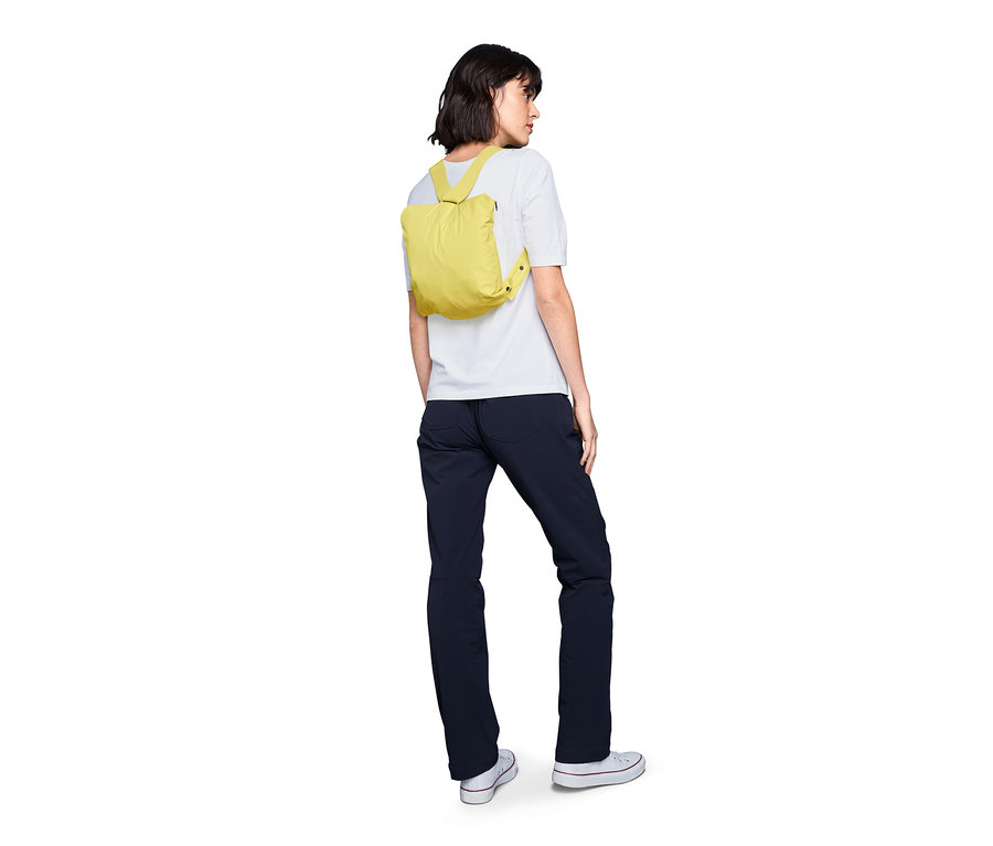 Kadın sırtında sarı renkli Hafif Yağmur Montu "Pack Me" taşıyor.