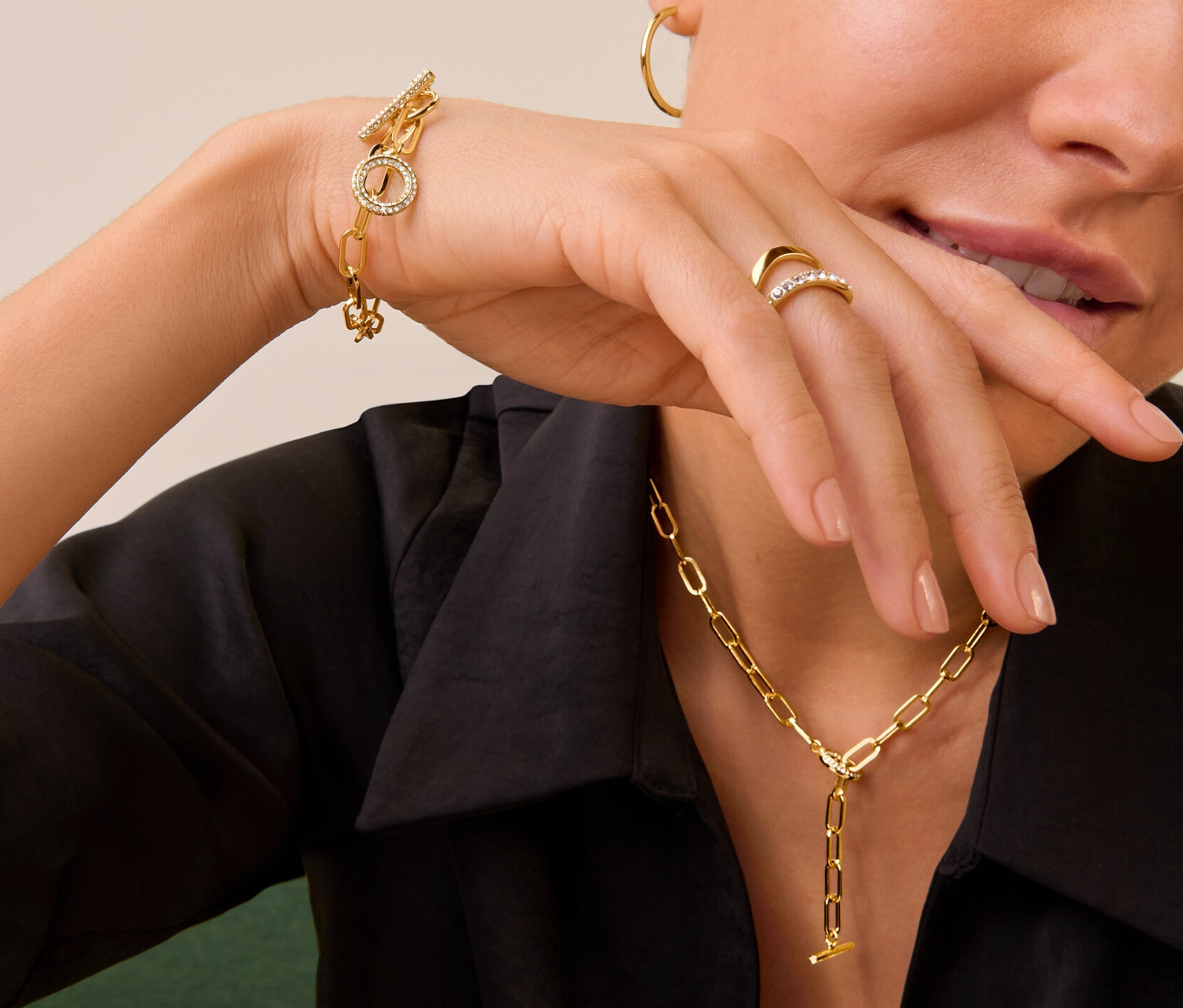 Kadın Çift Dalgalı Kristalli Yüzük, Kristal Taşlı Geçme Kolye ve Bileklik ve altın rengi Halka Küpe setini takıyor