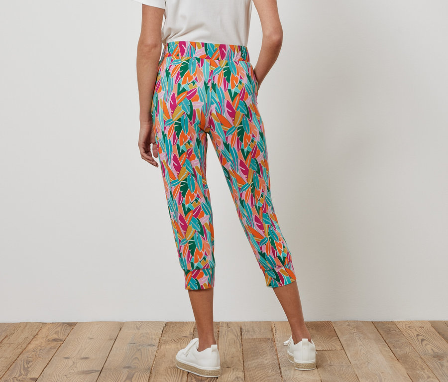 Kadın çok renkli 3/4 jarse pantolon ve beyaz spor ayakkabı giyiyor.