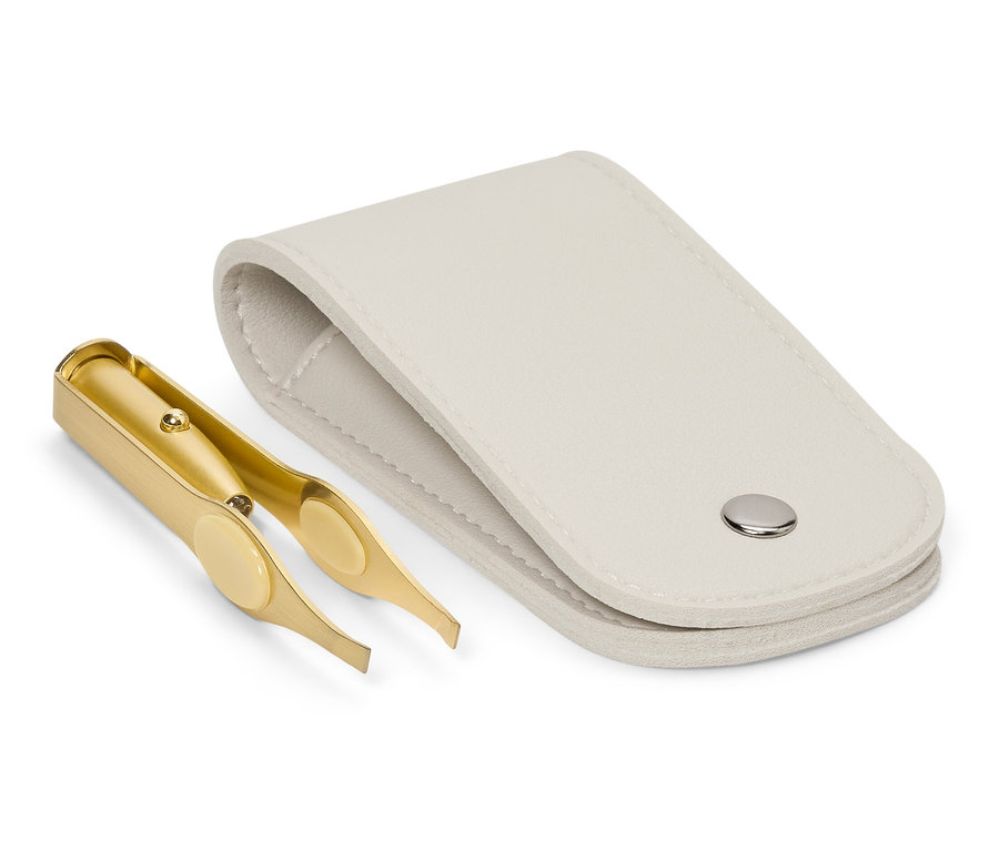 Altın renkli cımbız, açık beyaz bir kılıfın yanında duruyor.