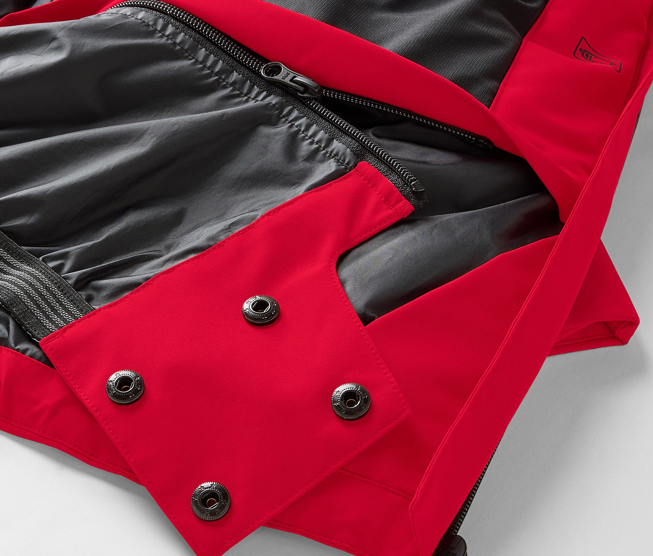 Siyah astarlı ve çıtçıtlı kırmızı bir ceketin yakın çekim detayı.