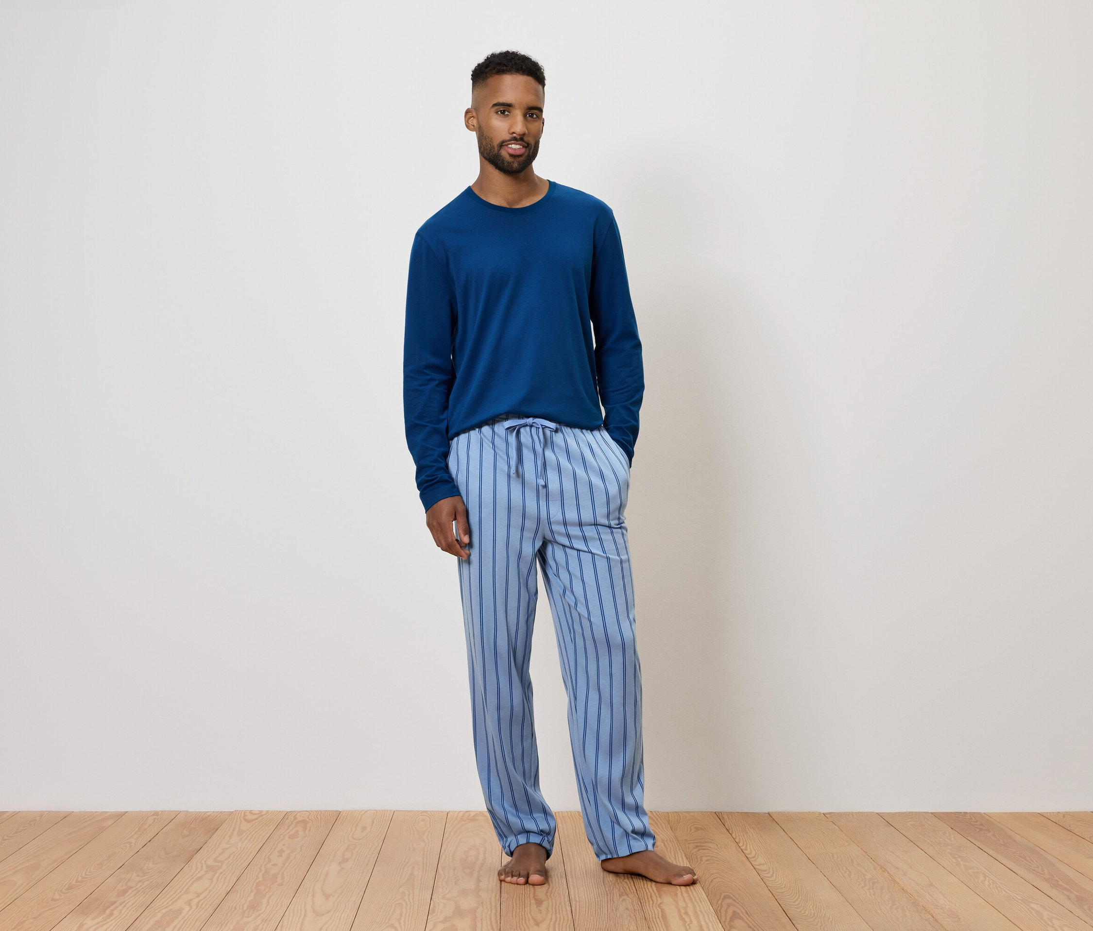 Mavi uzun kollu pijama ve çizgili pantolon giyen adam.