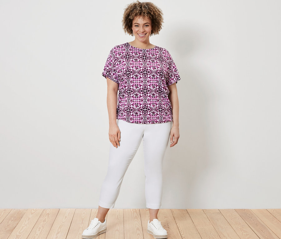 Kadın, Baskılı Berry Bluz ve Beyaz 7/8 Streç Pantolon ile poz veriyor.