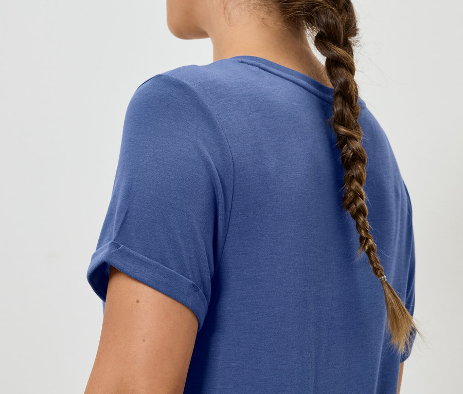 Örgülü saçlı kadın mavi tişört giyiyor.