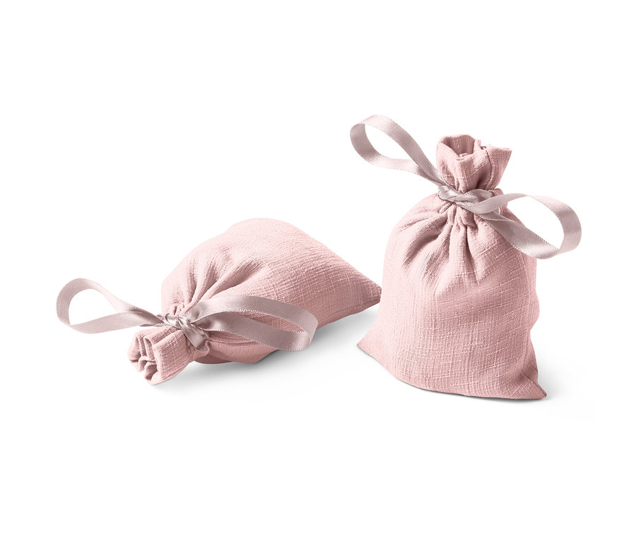 İki adet pembe renkli, kurdeleli koku kesesi, biri yatay, diğeri dikey duruyor.