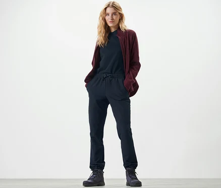 Sarışın bir kadın Softshell Jogging Pantolonun ceplerinde elleriyle duruyor.