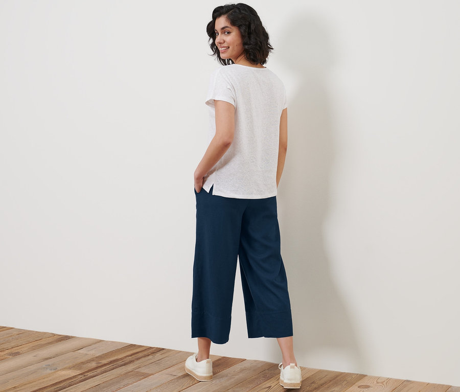 Kadın omzunun üzerinden bakıyor ve Keten Karışımlı Palazzo Pantolon ile poz veriyor.