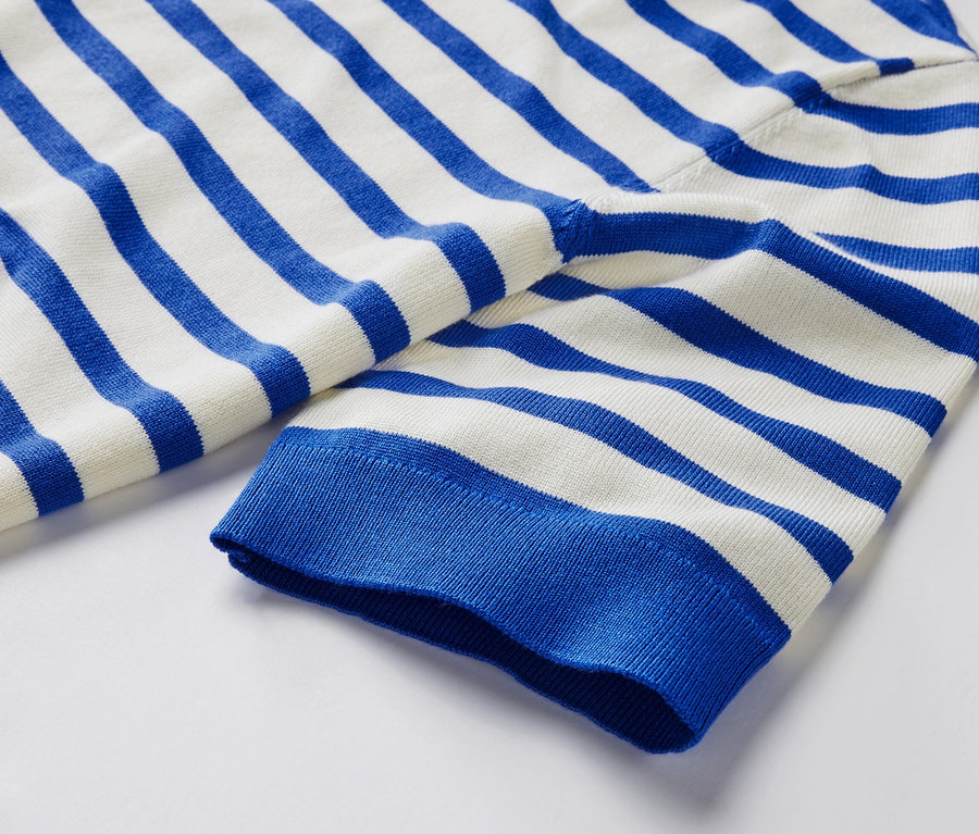 Çizgili, mavi ve beyaz renklerdeki ince örgülü kazağın yakın çekim detayı.