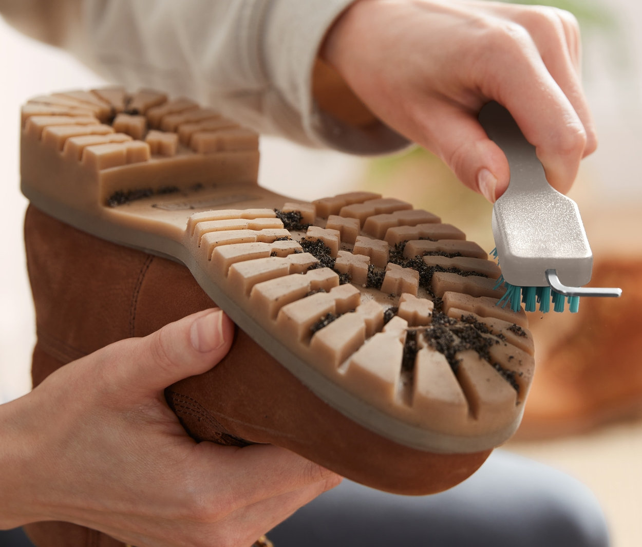 Bir kişi, İri Kir ve Ayakkabı Tabanı Temizleme Fırçası ile kahverengi bir botu temizliyor.