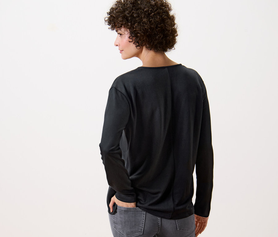 Arkası dönük bir kadın siyah bir bluz giyiyor.