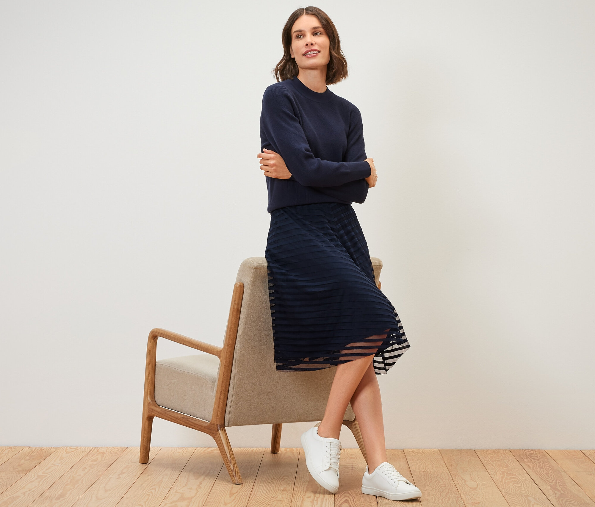 Bir kadın sandalyede oturuyor ve file etek giyiyor.