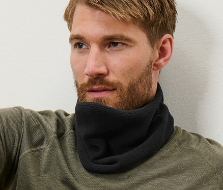 Kahverengi saçlı adam oturuyor ve siyah polar yaka takıyor.