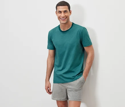 Adam beyaz bir arka planda Şortlu Pijama Takımı ile poz veriyor.