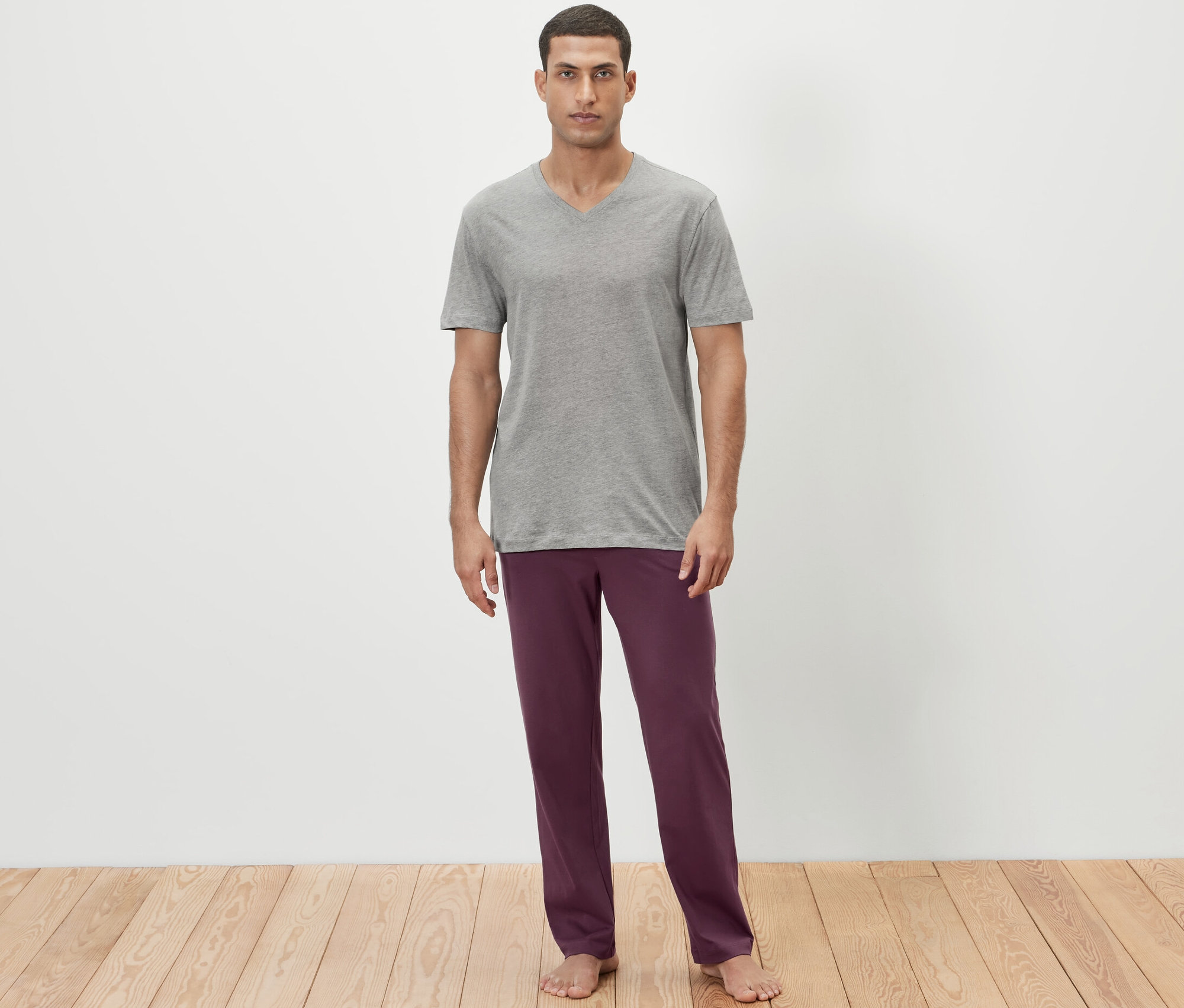Adam gri bir tişört ve bordo pijama altı giyiyor.