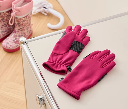 Pembe eldivenler, pembe çocuk çizme ve beyaz bir şemsiyenin yanında krem rengi bir masanın üzerinde duruyor.