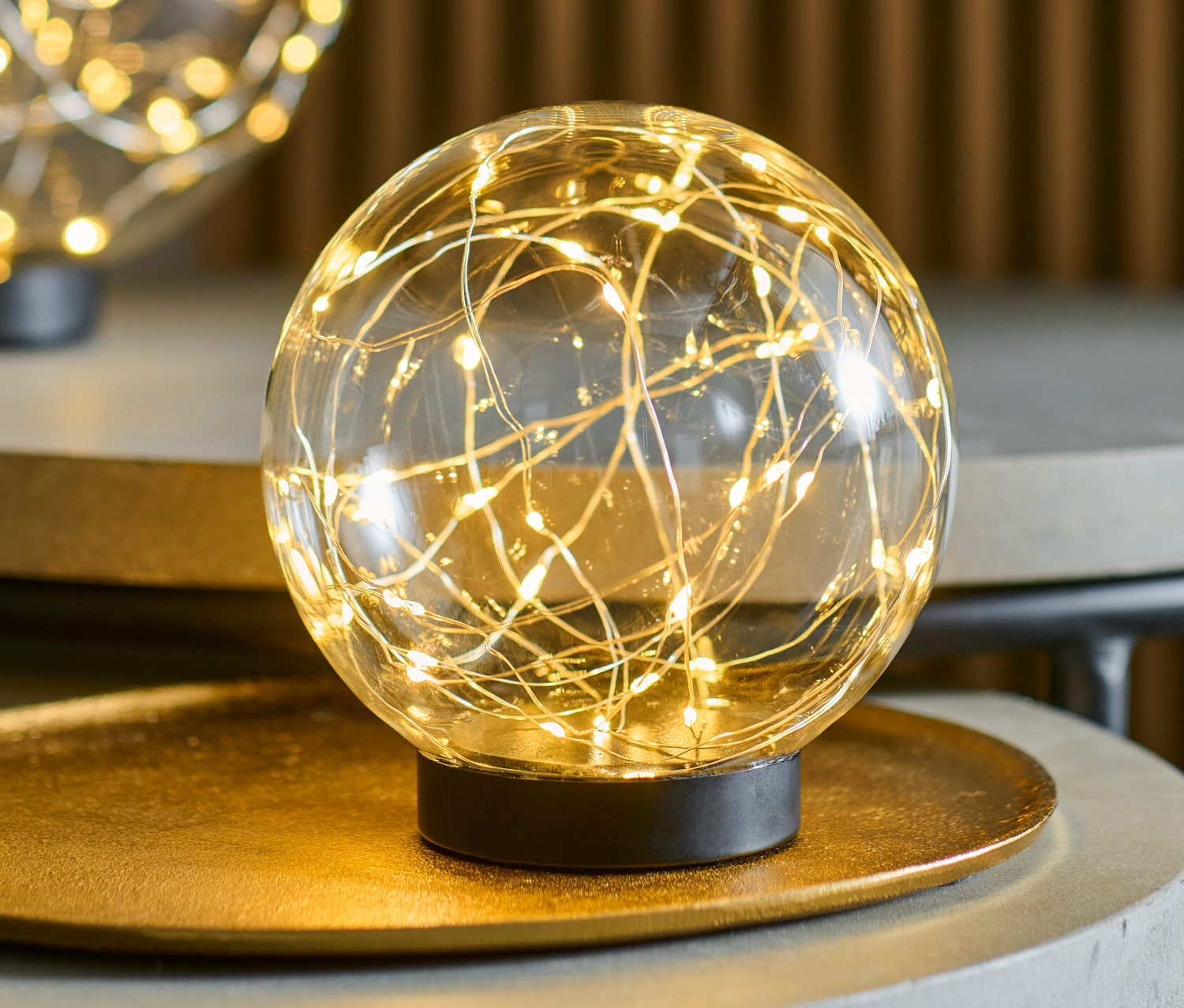 İki adet, her biri yaklaşık 15 cm çapında LED cam küre, gri masaların üzerinde duruyor.