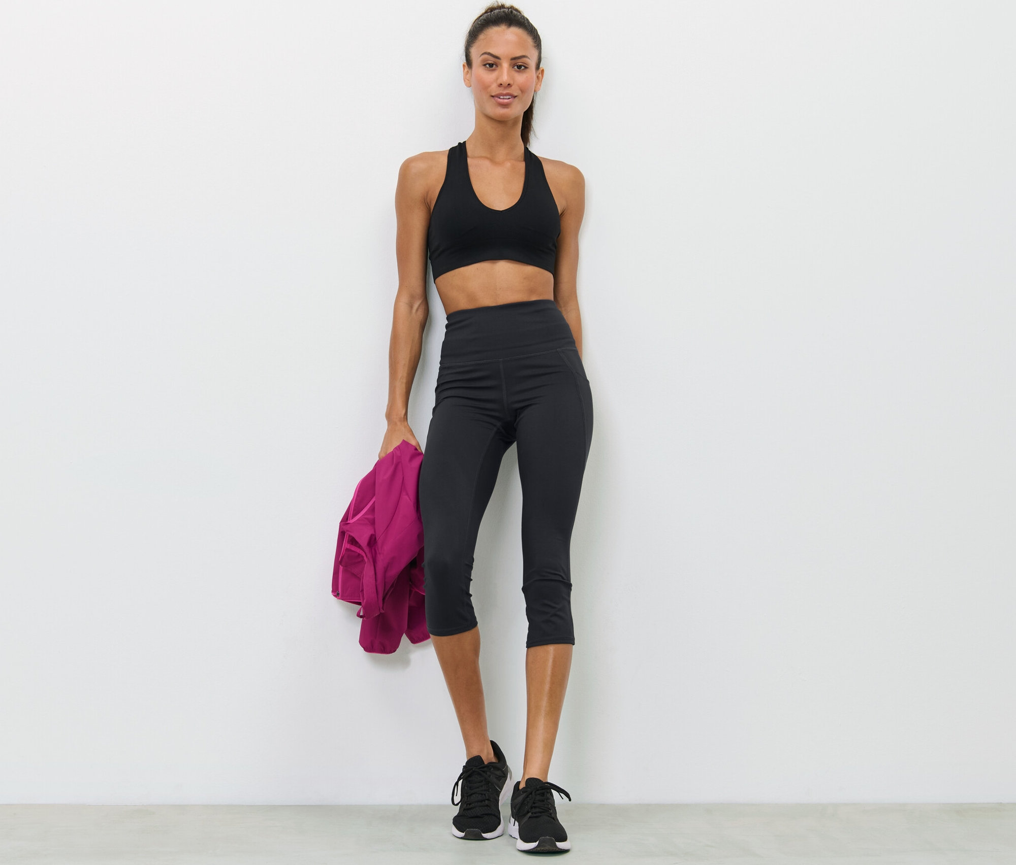 Kadın spor sütyeni ve siyah 3/4 spor tayt ile poz veriyor.