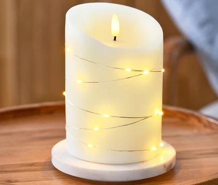 Yuvarlak ahşap bir masanın üzerinde mikro LED ışık zincirli gerçek balmumu LED mum duruyor.
