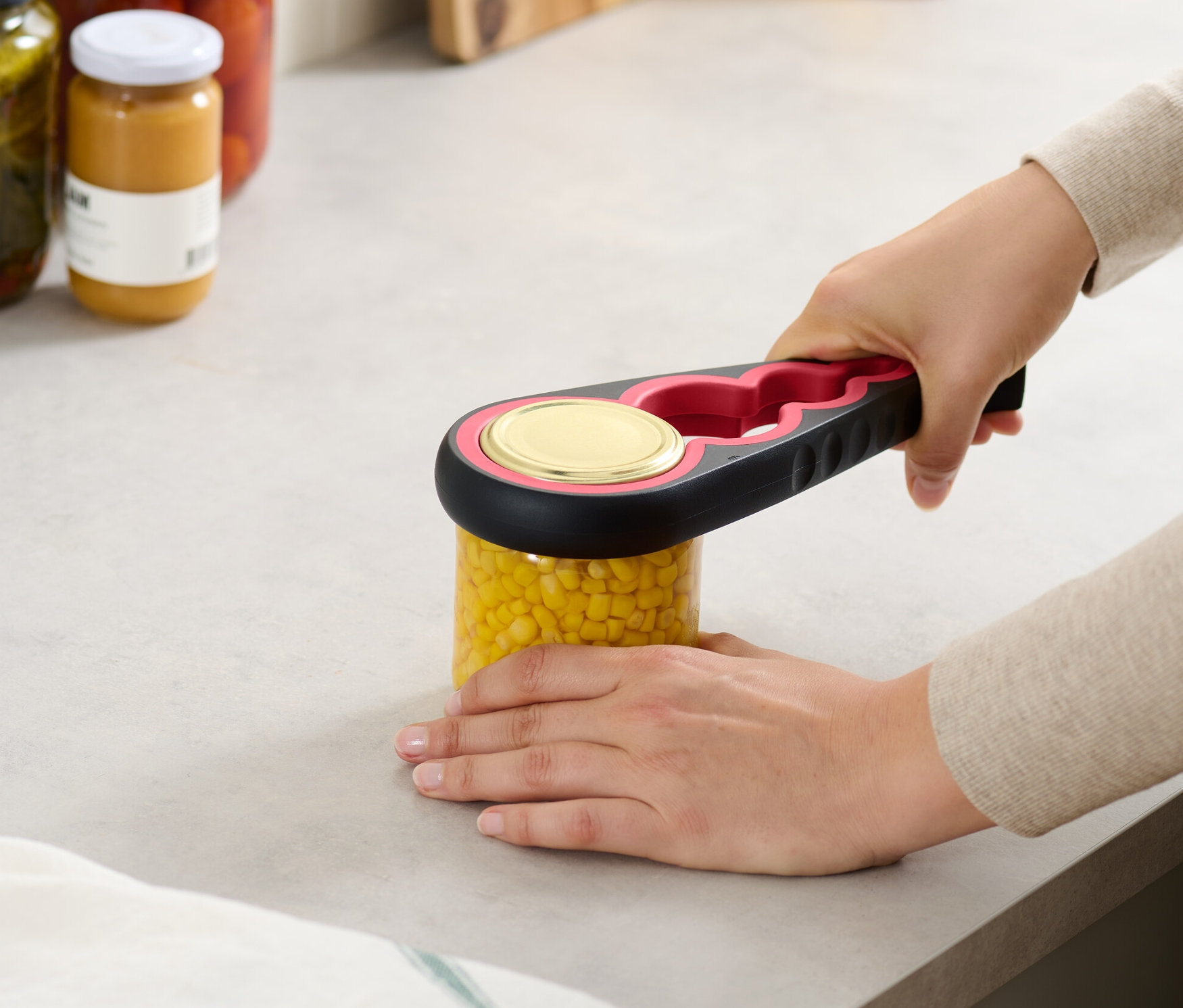 Kadın, Kavanoz ve Şişe Açacağı ile bir kavanoz mısır açıyor.